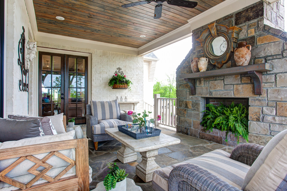 Cette image montre un porche d'entrée de maison arrière traditionnel de taille moyenne avec un foyer extérieur, des pavés en pierre naturelle et une extension de toiture.
