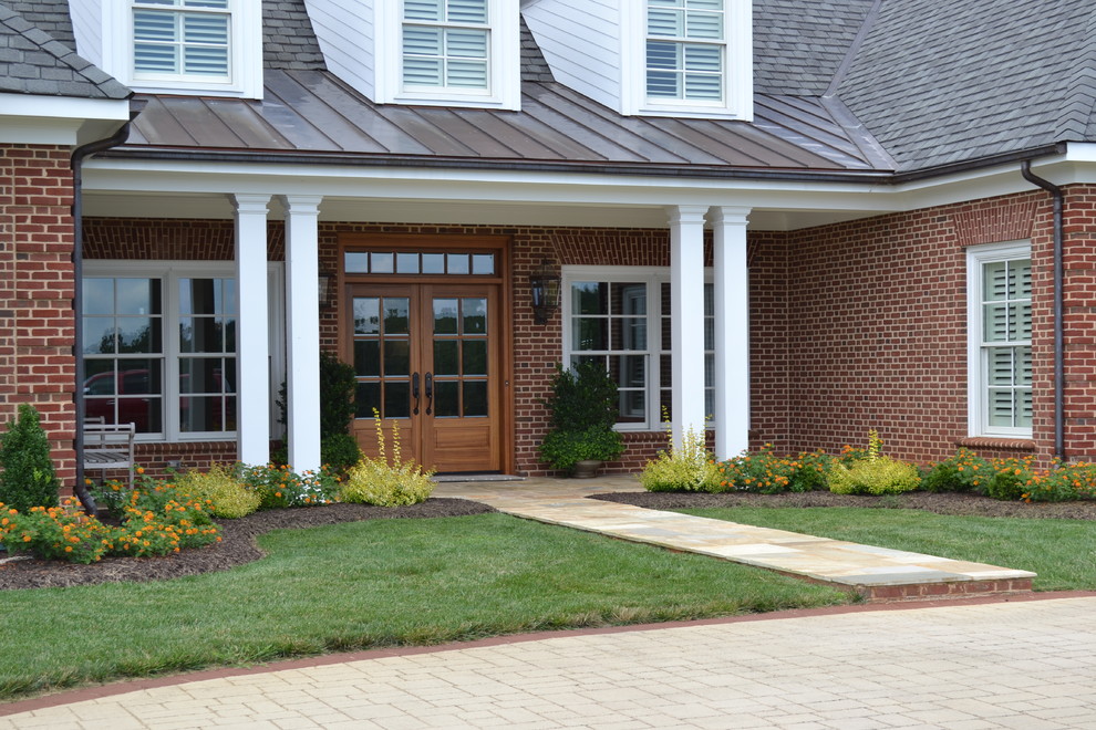Small elegant stone front porch photo in Other with a roof extension