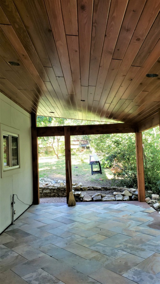 Exemple d'un grand porche d'entrée de maison arrière éclectique avec du carrelage et une extension de toiture.