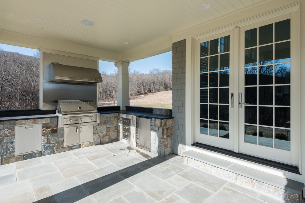 Imagen de terraza clásica de tamaño medio en patio trasero y anexo de casas con cocina exterior y adoquines de piedra natural