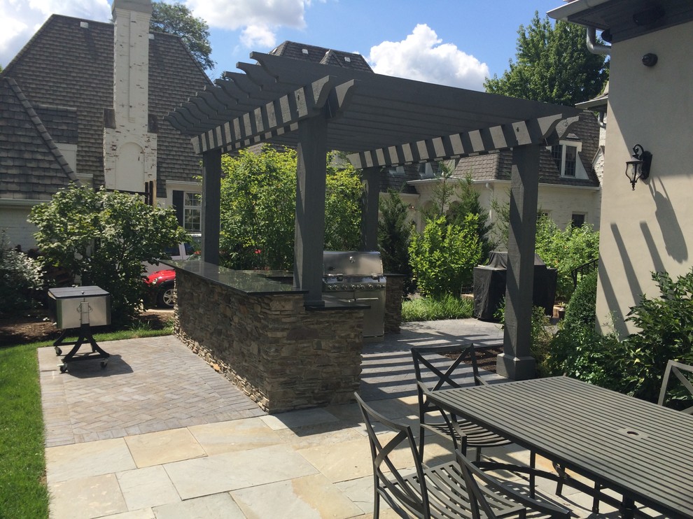 Foto de terraza de estilo americano de tamaño medio en patio trasero con cocina exterior, adoquines de piedra natural y pérgola