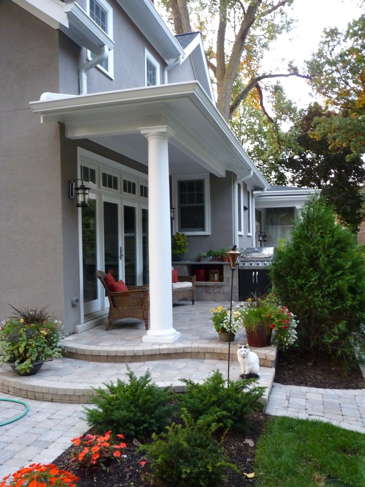 This is an example of a side veranda in Chicago with an outdoor kitchen, natural stone paving and a roof extension.