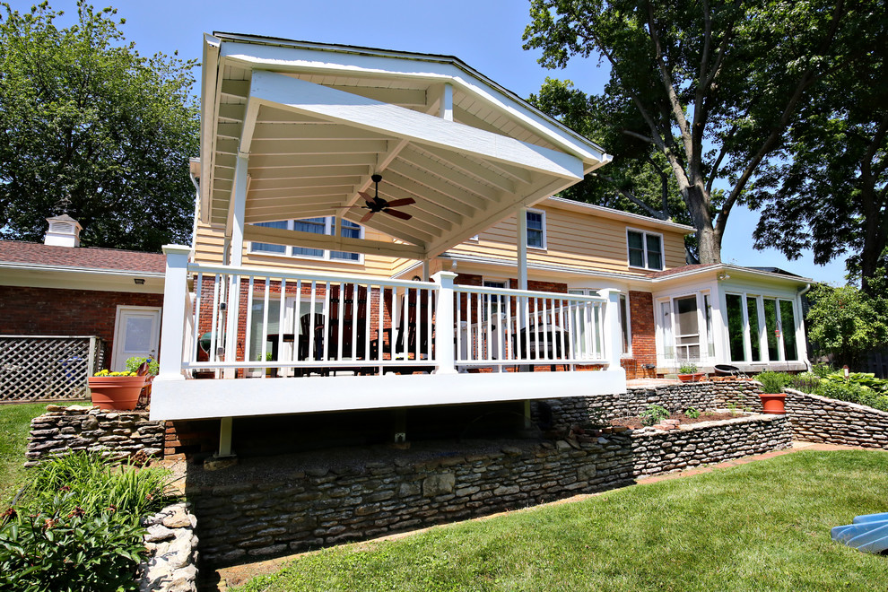 Imagen de terraza clásica de tamaño medio en patio trasero y anexo de casas con entablado