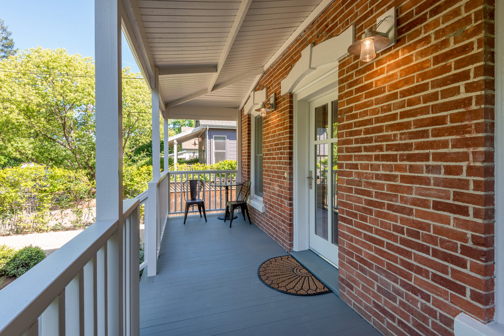 Idée de décoration pour un porche d'entrée de maison avant tradition avec une terrasse en bois et une extension de toiture.