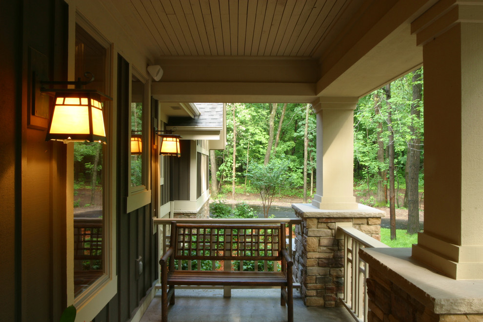 Inredning av en rustik stor veranda framför huset, med stämplad betong och takförlängning