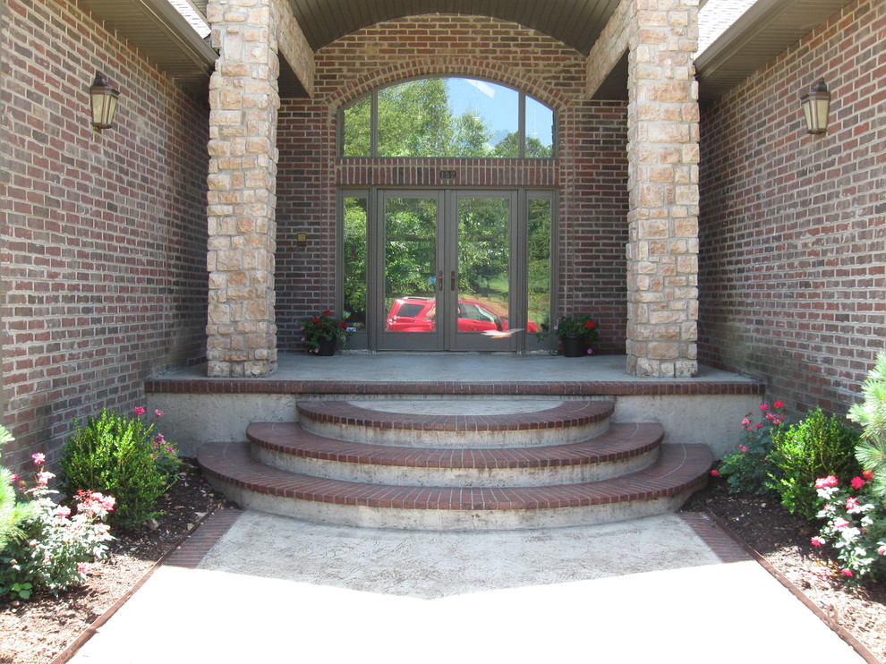 Immagine di un grande portico tradizionale davanti casa con cemento stampato e un tetto a sbalzo
