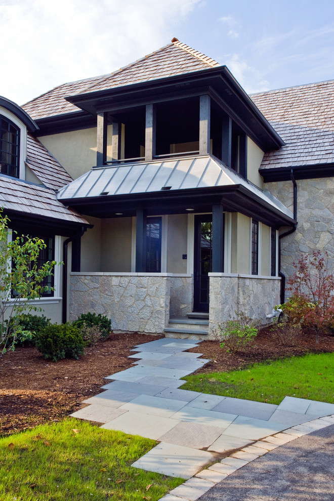 Large classic stone front porch idea in Chicago with a roof extension