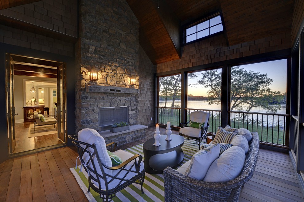 Idée de décoration pour un porche d'entrée de maison tradition avec un foyer extérieur, une terrasse en bois et une extension de toiture.