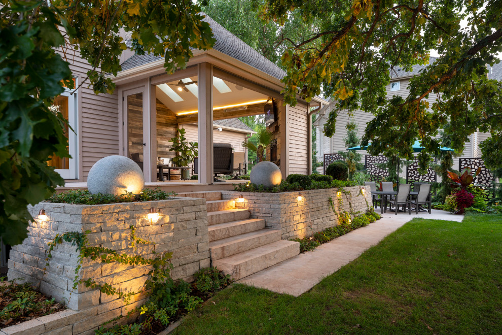 На фото: веранда среднего размера на заднем дворе в классическом стиле с уличным камином, покрытием из каменной брусчатки и навесом
