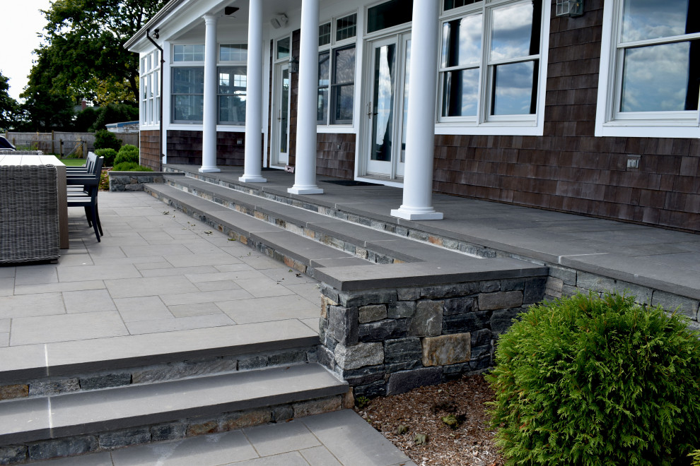 Photo of a large classic back veranda in Providence with an outdoor kitchen and natural stone paving.