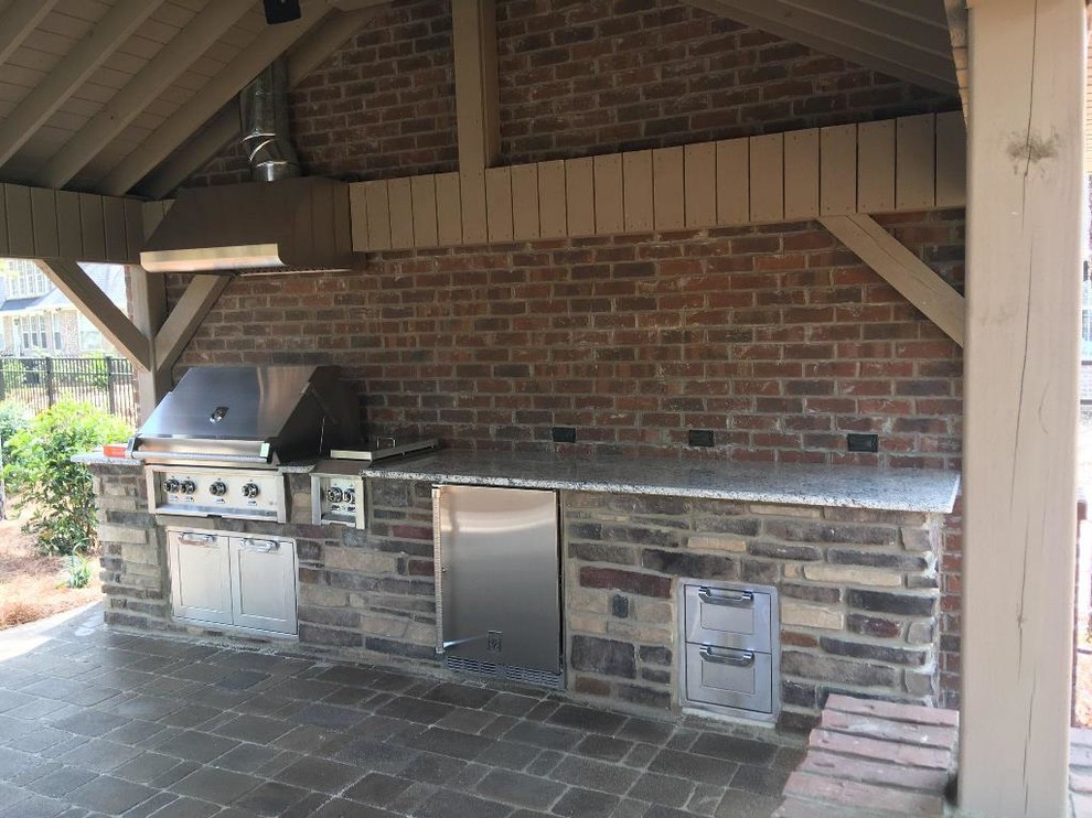 Aménagement d'un grand porche d'entrée de maison arrière classique avec une cuisine d'été et des pavés en brique.