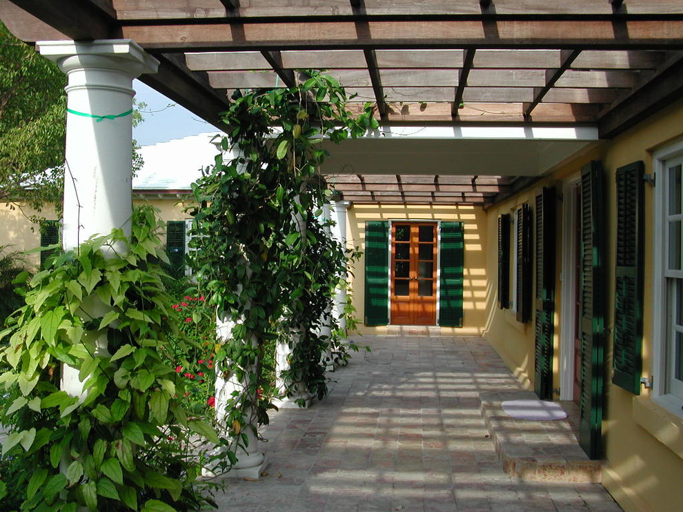 Ispirazione per un ampio portico tropicale davanti casa con pavimentazioni in pietra naturale e una pergola