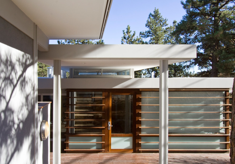 Idées déco pour un porche d'entrée de maison moderne avec une terrasse en bois et une extension de toiture.