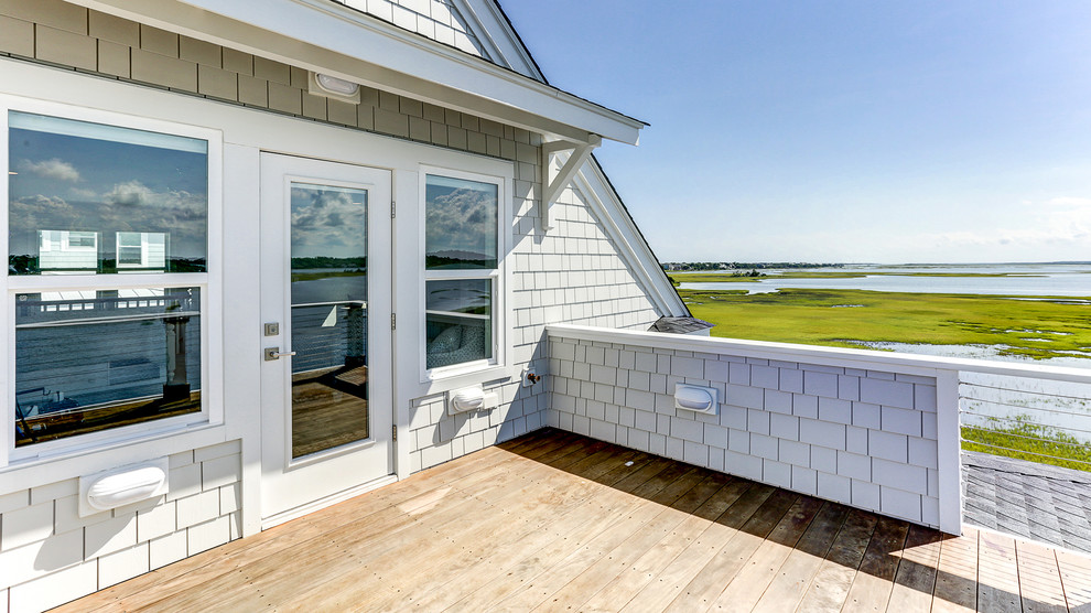 Exemple d'un porche d'entrée de maison arrière bord de mer avec une moustiquaire, une terrasse en bois et une extension de toiture.