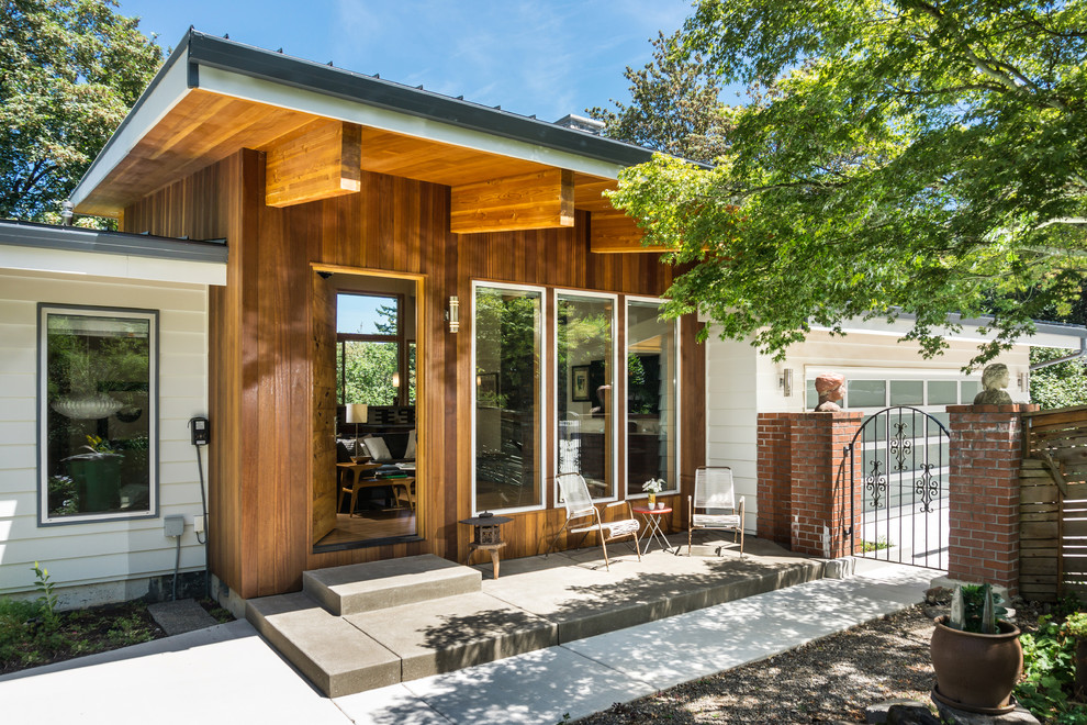 Immagine di un portico minimalista di medie dimensioni e dietro casa con lastre di cemento e un tetto a sbalzo