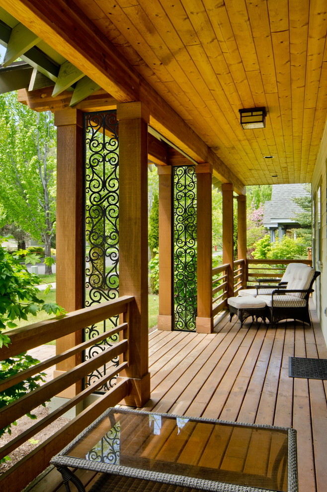 Réalisation d'un grand porche d'entrée de maison avant craftsman avec une terrasse en bois et une extension de toiture.