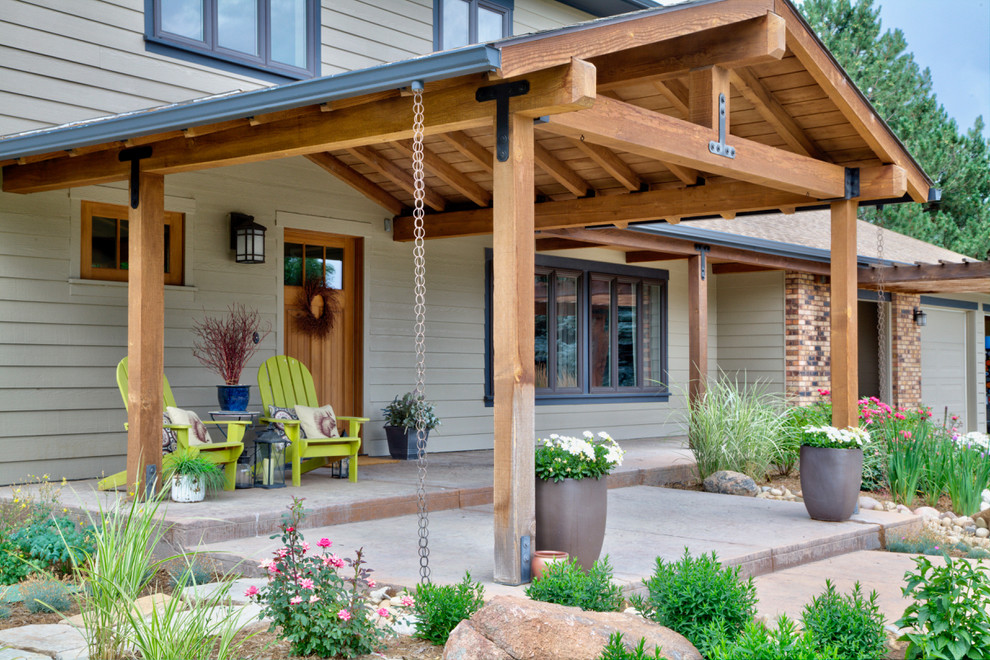 This is an example of a large rustic concrete front porch design in Denver with a roof extension.