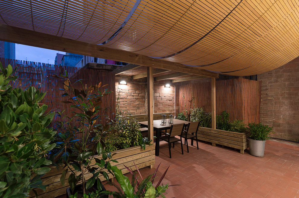 Foto di un portico mediterraneo dietro casa con un giardino in vaso, pavimentazioni in mattoni e un tetto a sbalzo