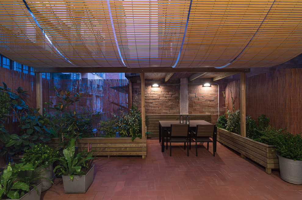 Идея дизайна: веранда на заднем дворе в средиземноморском стиле с растениями в контейнерах, мощением клинкерной брусчаткой и навесом
