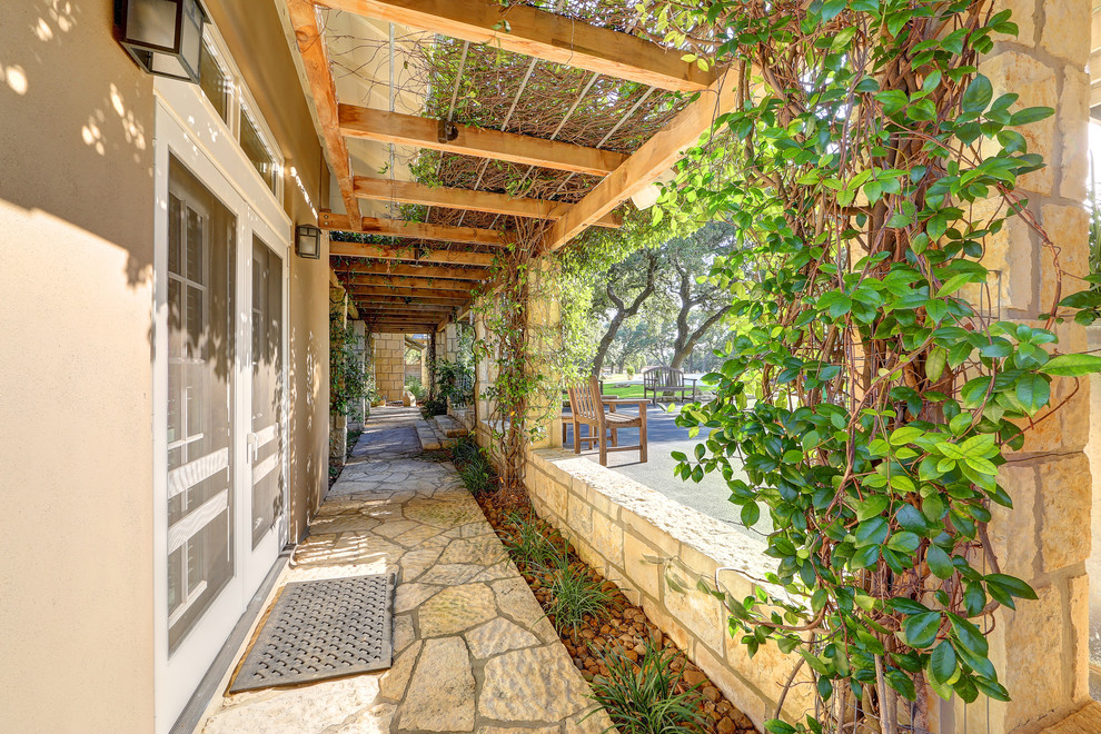 Modelo de terraza de estilo de casa de campo con adoquines de piedra natural y pérgola