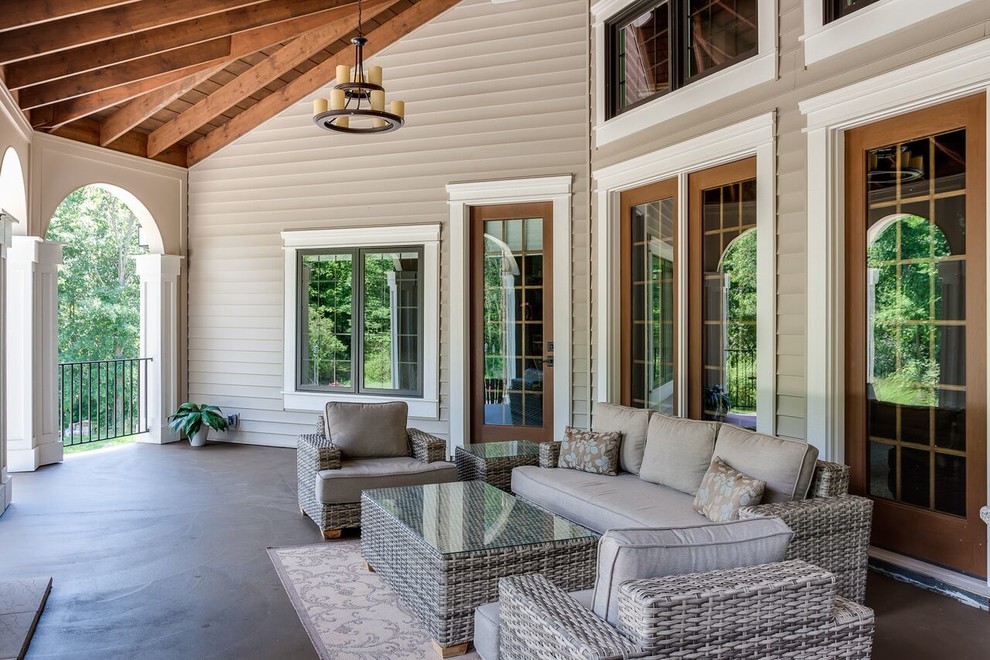 Aménagement d'un grand porche d'entrée de maison arrière classique avec une dalle de béton et une extension de toiture.