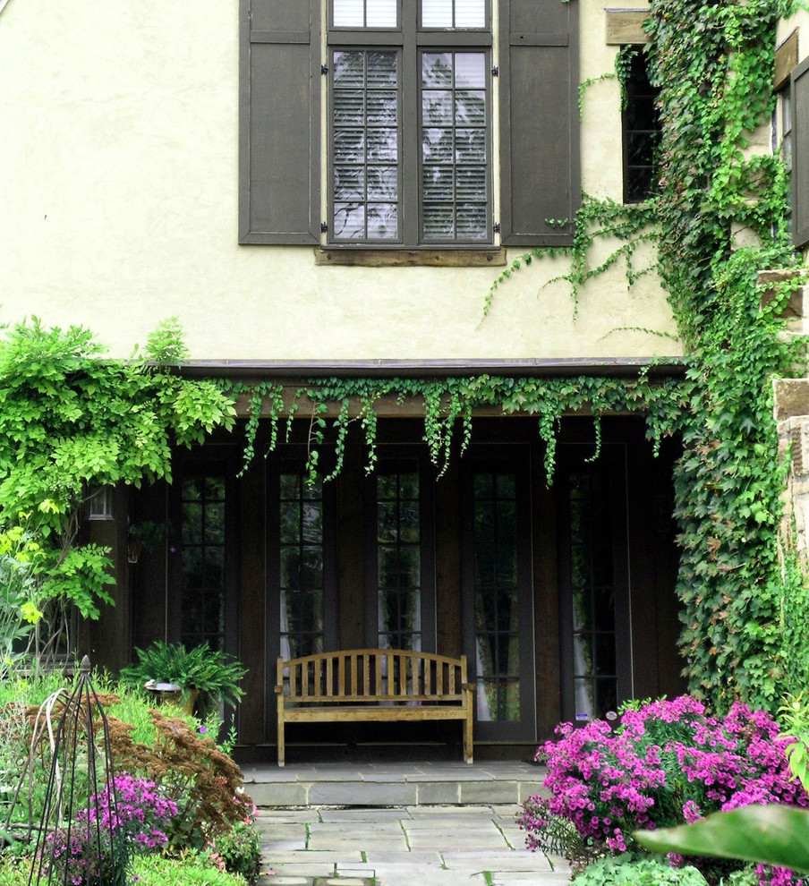Immagine di un portico chic di medie dimensioni e davanti casa con un tetto a sbalzo e pavimentazioni in pietra naturale