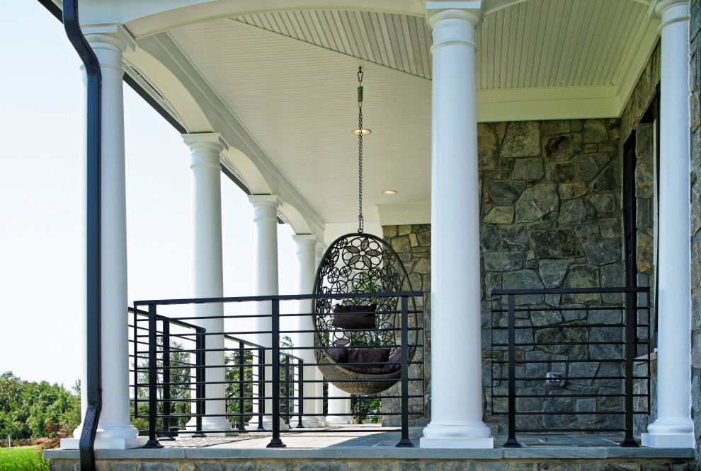 Imagen de terraza columna tradicional extra grande en patio delantero y anexo de casas con adoquines de piedra natural, barandilla de metal y columnas