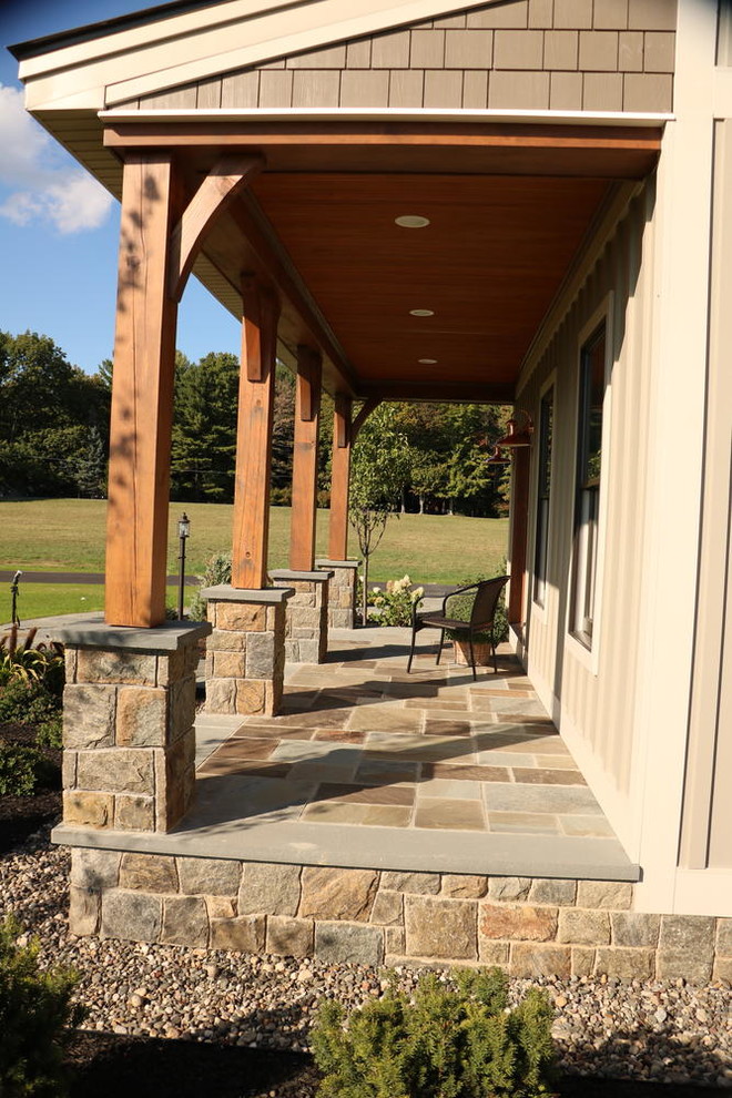 Inspiration for a large country stone front porch remodel in Boston with an awning