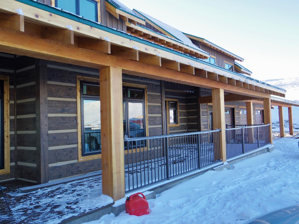 This is an example of a large rustic front porch design in Calgary with a roof extension.
