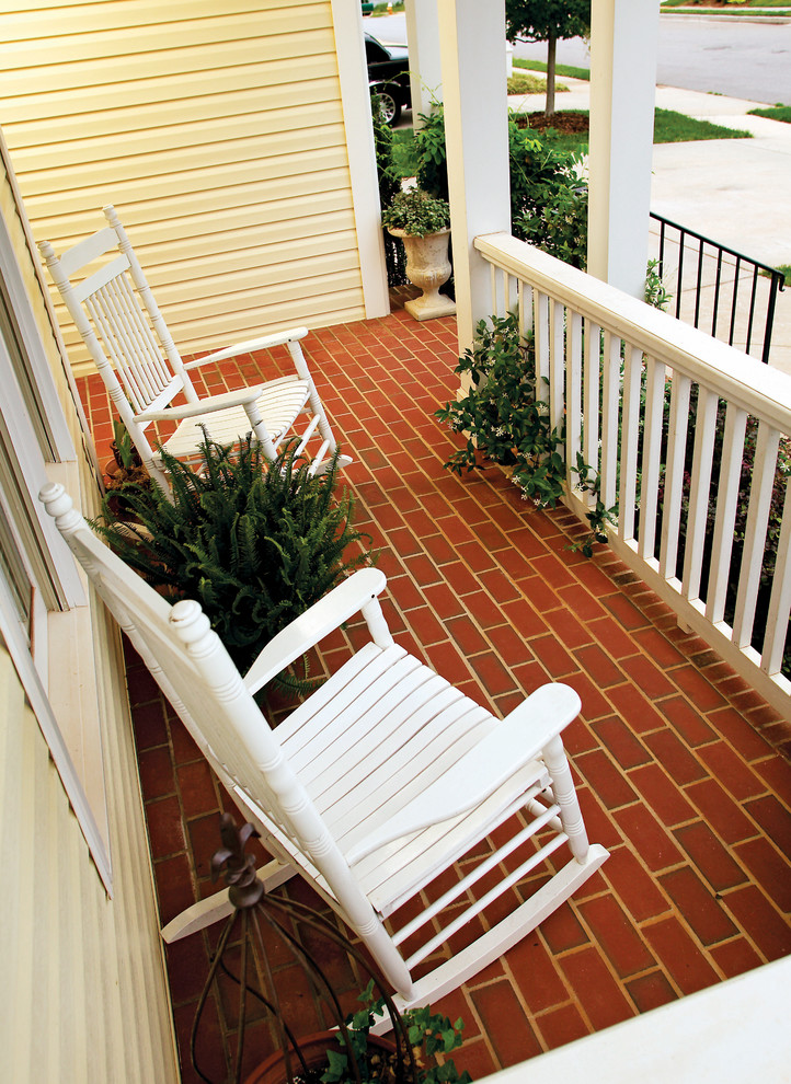 This is an example of a small traditional front porch design in Charlotte with a roof extension.