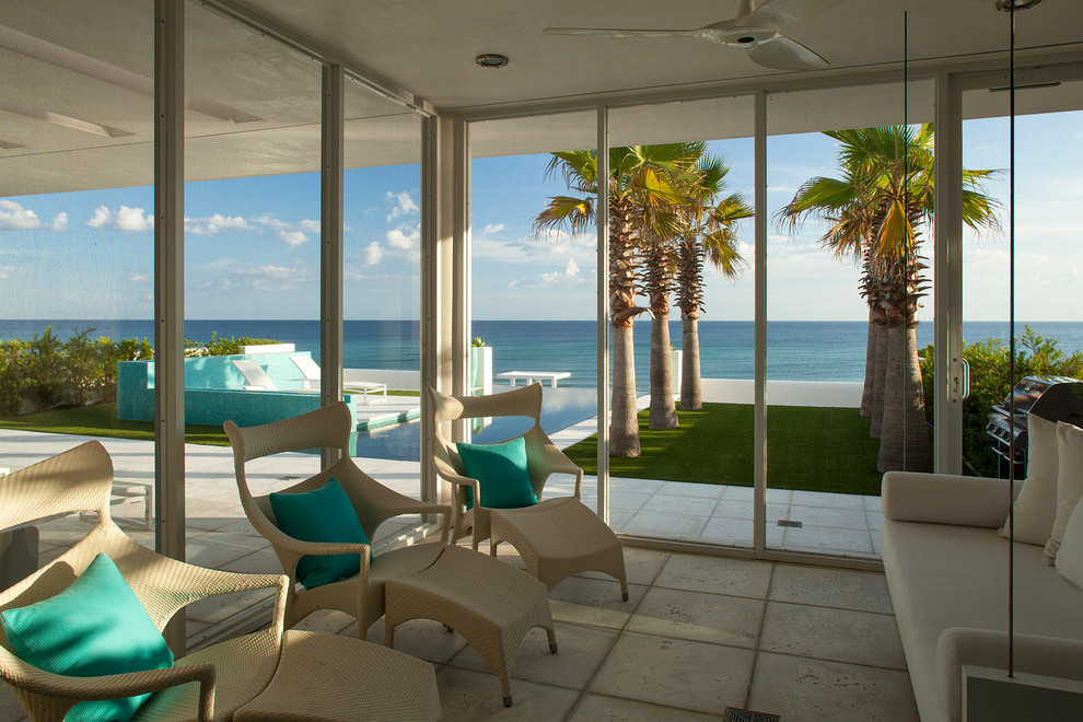 Inspiration for a large contemporary back screened veranda in Miami with natural stone paving and a roof extension.