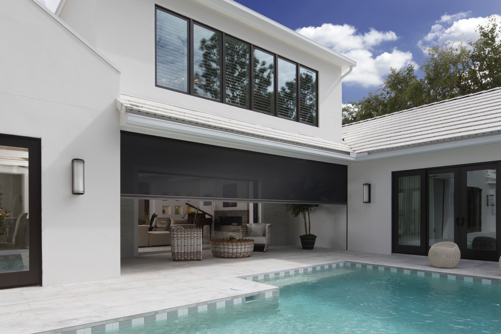 This is an example of a large modern back screened veranda in Orlando with concrete slabs and a roof extension.