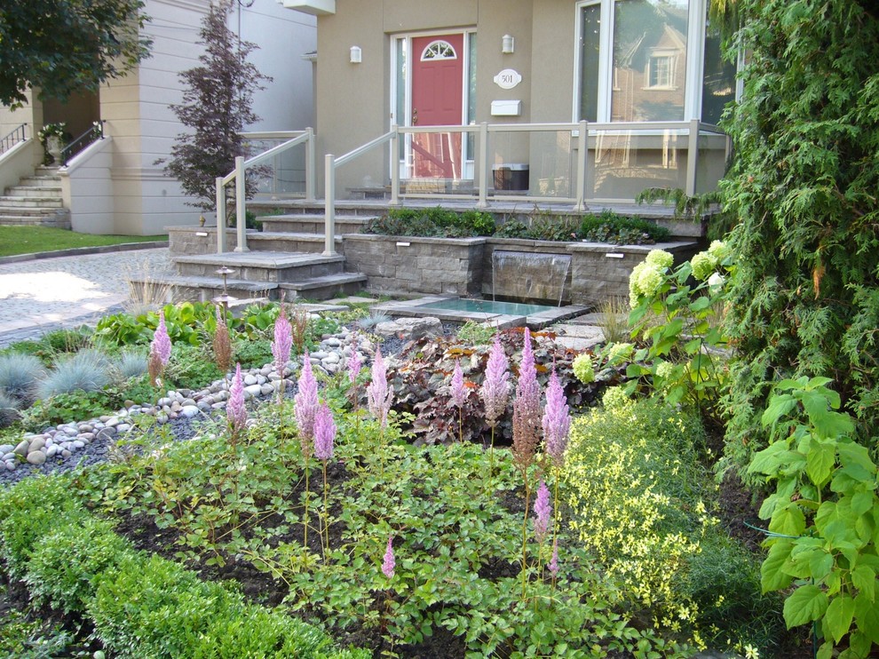 Ejemplo de terraza tradicional de tamaño medio en patio delantero con fuente y adoquines de piedra natural