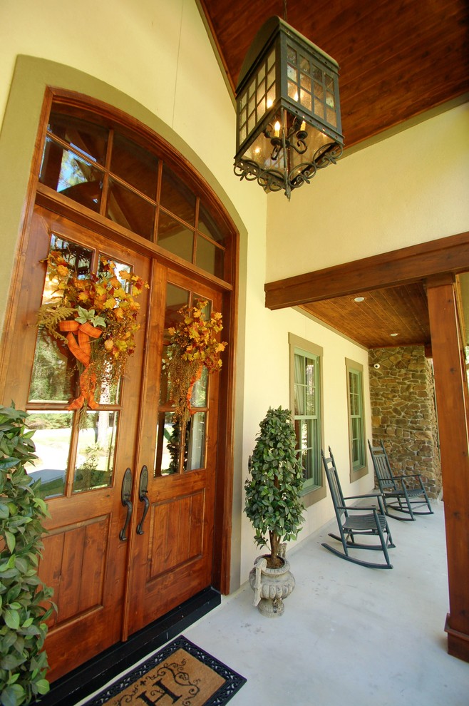 Mountain style concrete front porch photo in Houston with a roof extension