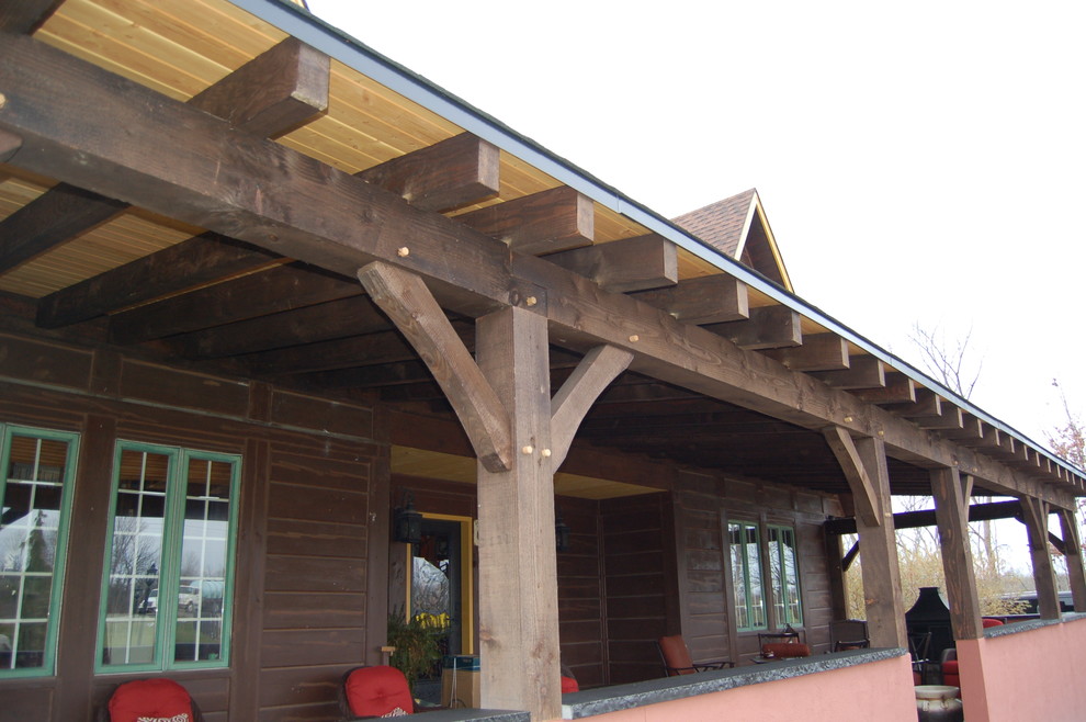 Esempio di un grande portico stile rurale davanti casa con un focolare, pavimentazioni in mattoni e un tetto a sbalzo