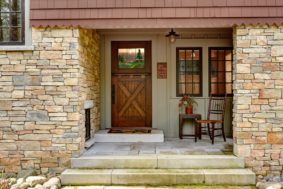 Inspiration for a rustic concrete paver front porch remodel in Minneapolis with a roof extension