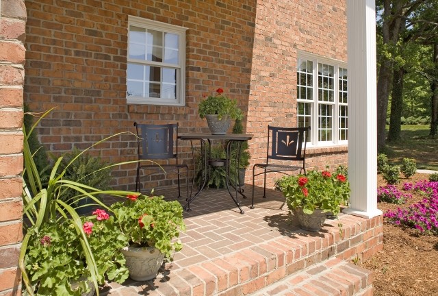 Klassisk inredning av en liten veranda framför huset, med marksten i tegel och takförlängning