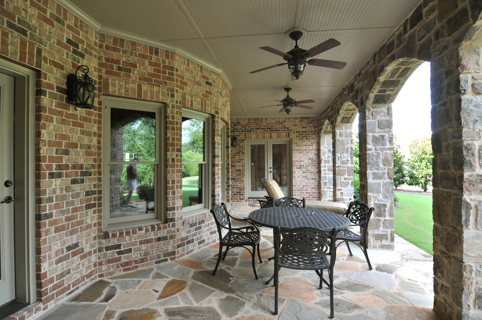 Cette photo montre un porche d'entrée de maison arrière chic avec des pavés en pierre naturelle et une extension de toiture.