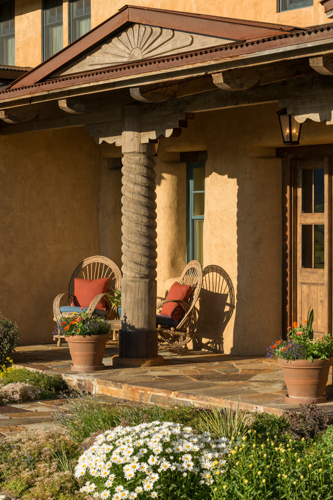 Exemple d'un porche d'entrée de maison sud-ouest américain avec des pavés en pierre naturelle et une extension de toiture.