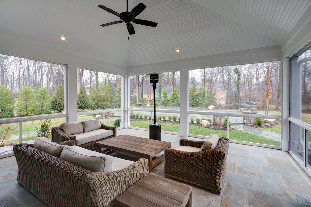 Transitional stone screened-in back porch idea in DC Metro with a roof extension