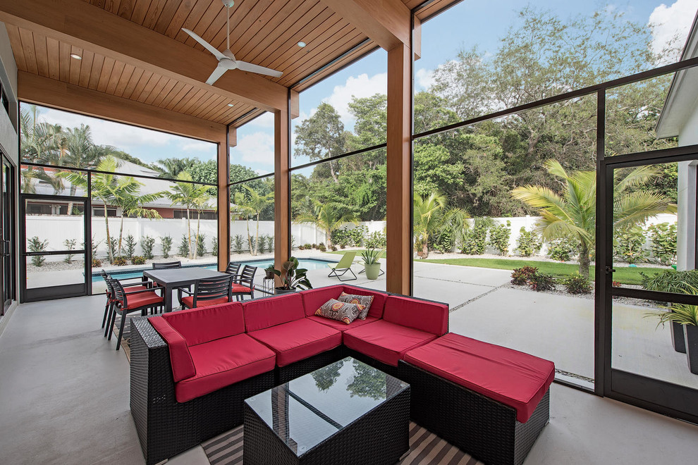 Cette photo montre un porche d'entrée de maison arrière moderne avec une moustiquaire, une dalle de béton et une extension de toiture.