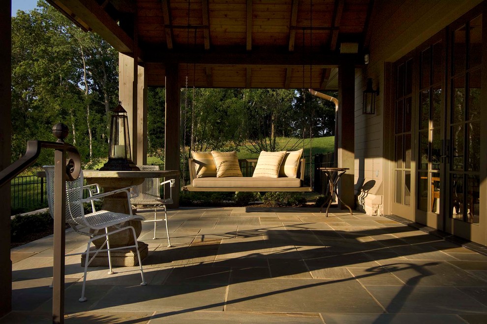 Exempel på en stor eklektisk veranda på baksidan av huset, med naturstensplattor och takförlängning