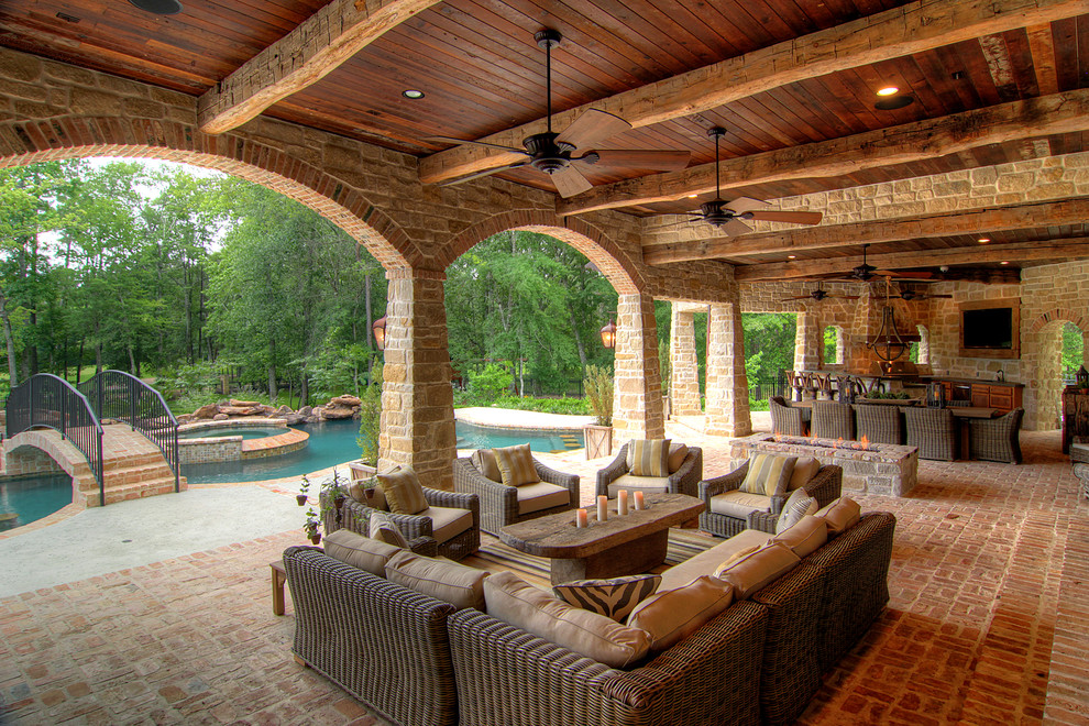 Inspiration for a mediterranean brick porch remodel in Houston with a fire pit and a roof extension