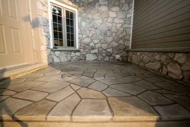 This is an example of a small mediterranean stamped concrete back porch design in St Louis with a roof extension.