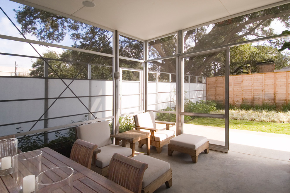 Cette photo montre un grand porche d'entrée de maison latéral moderne avec une moustiquaire et une dalle de béton.