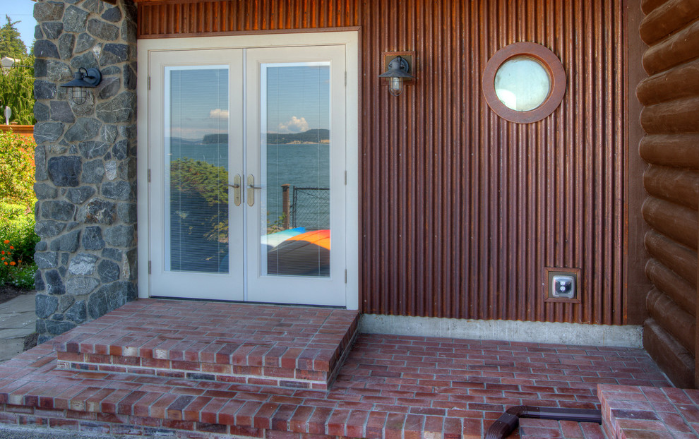 Idéer för en liten rustik veranda på baksidan av huset, med marksten i tegel och takförlängning