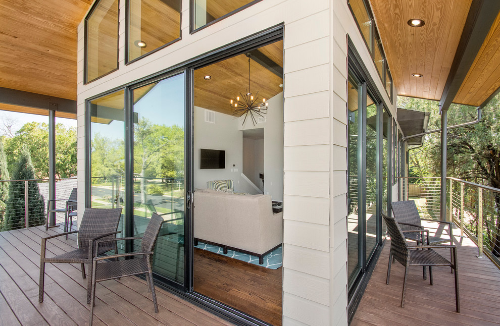 Idées déco pour un grand porche d'entrée de maison avant rétro avec une terrasse en bois et une extension de toiture.
