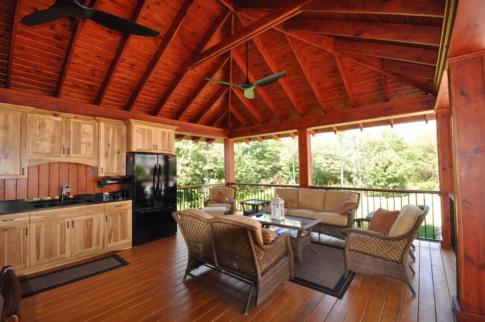 Cette image montre un grand porche d'entrée de maison arrière traditionnel avec une cuisine d'été et un auvent.