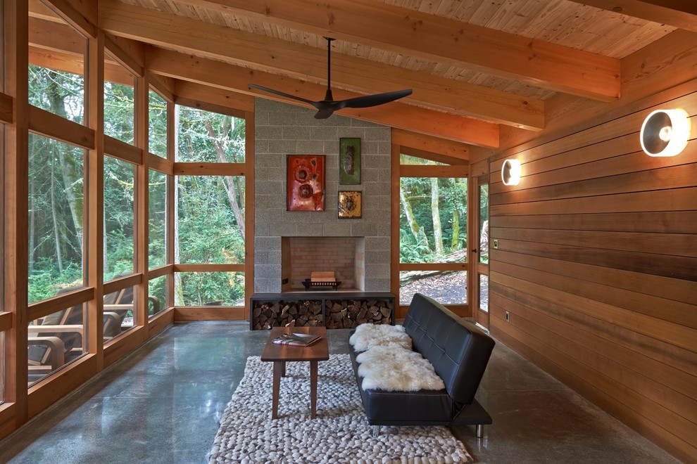 Cette image montre un grand porche d'entrée de maison arrière chalet avec un foyer extérieur, une dalle de béton et une extension de toiture.