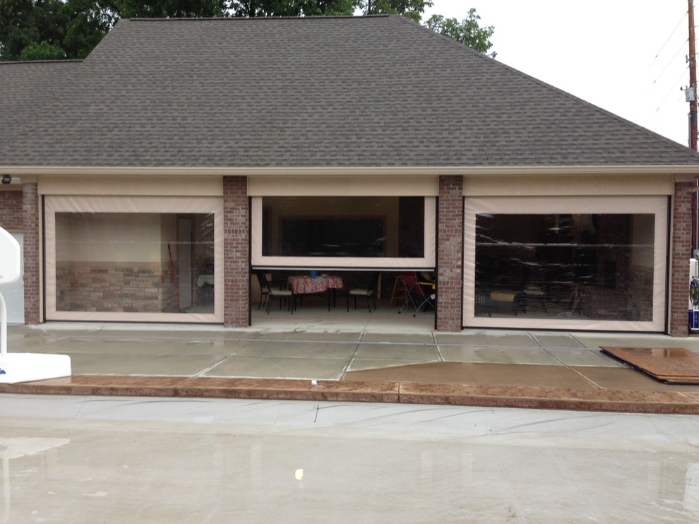 Immagine di un grande portico classico dietro casa con un portico chiuso, lastre di cemento e un tetto a sbalzo